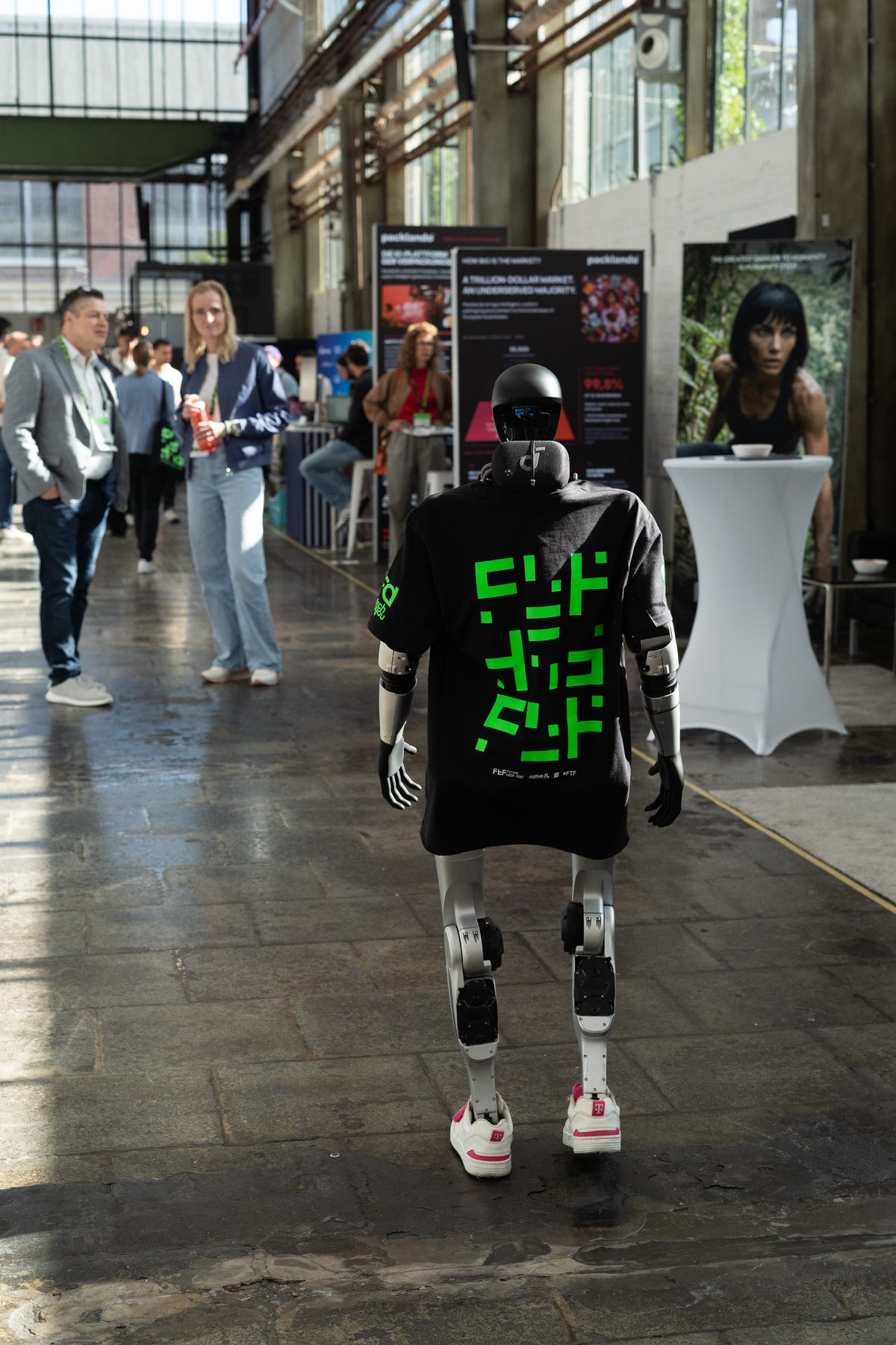 Roboter im T-Shirt läuft durch die Messehalle