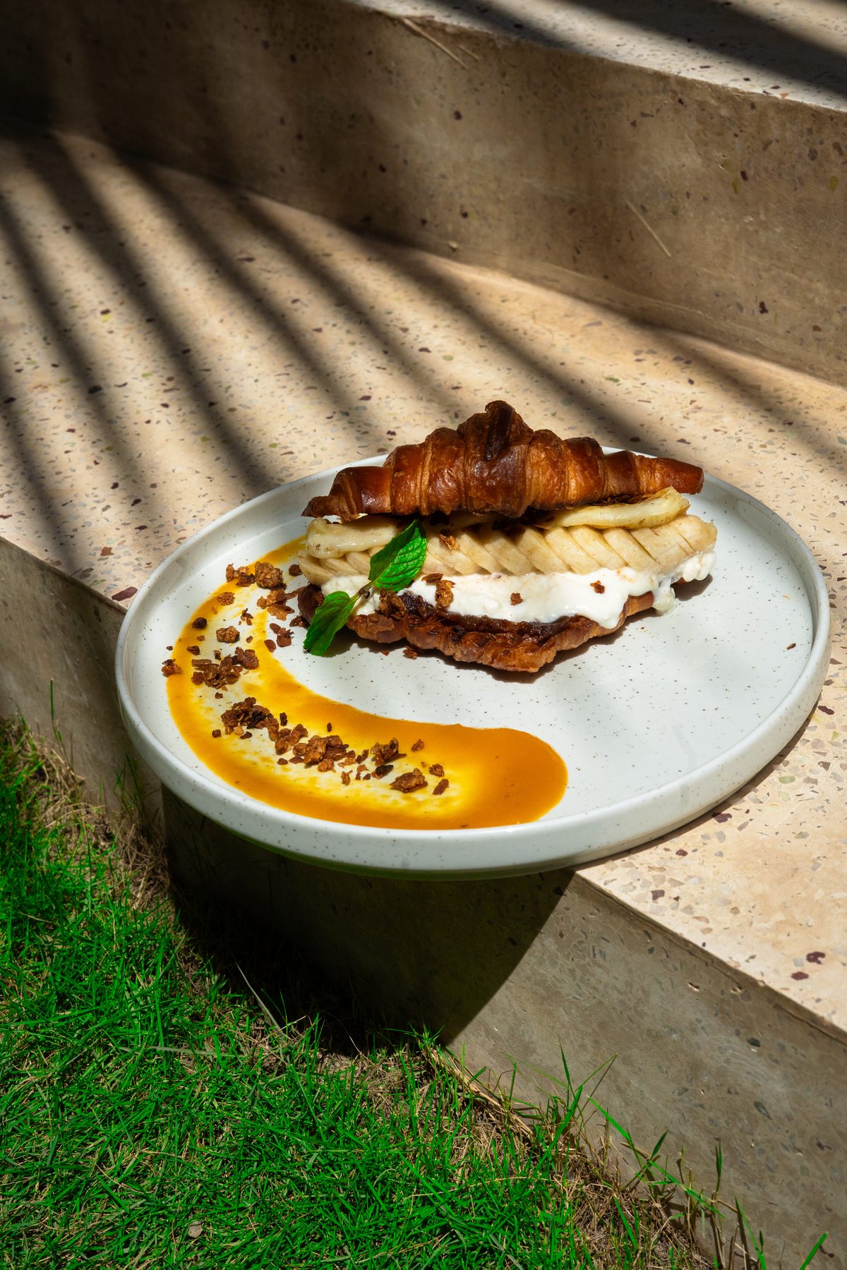 Croissant mit Banane und Mangosauce auf Terrazzo, Lamellenschatten